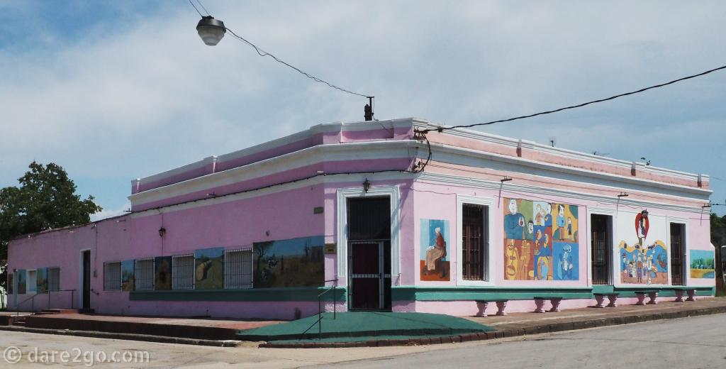 Pink corner building in 25 de Agosto with a collection of murals