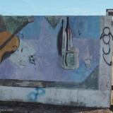 Mural in Pan de Azucar: still life with guitar, bottles and drink glasses. This one is at the entrance of a derelict apartment block.