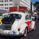 A classic Volkswagen Beetle with a fancy Coca-Cola design, complete with crates on the roof.