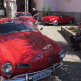 Several Type 14 Volkswagen Karmann Ghia in bright red. In the foreground coupe style bodies, in the background one convertible.