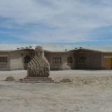 A hotel built from salt bricks at the edge of the Salar de Uyuni. In front a salt brick statue celebrating the visit of the Dakar rally.