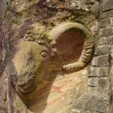An unfinished carving of a ram's head on the exterior wall of the Castillo de Lamas.
