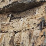 The remains of a broken sarcophagus on a ledge down and to the right of the other 6 at the Karajia cliff tombs.