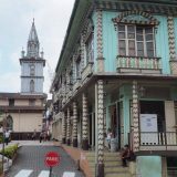 Visiting Zaruma: wooden buildings along the plaza, with the church in the background.