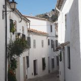 Grazalema: another narrow street edged by white-washed houses, which are adorned with flowering plants.