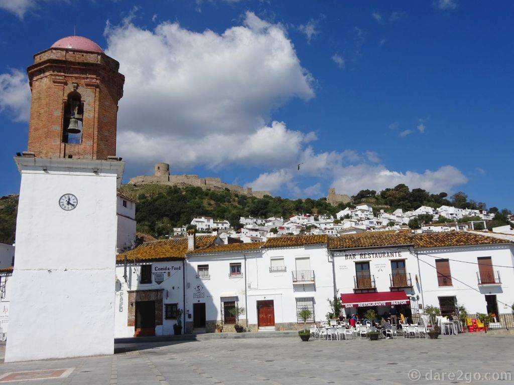 Plaza de la Constitución in Jimena de la Frontera: amazing view of the castle, outdoor restaurant in the sun, and the bell tower of the Santa Maria la Coronado Church.