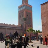 A horse drawn carriage passes in front of the Kasbah Mosque, with its decorative minaret.