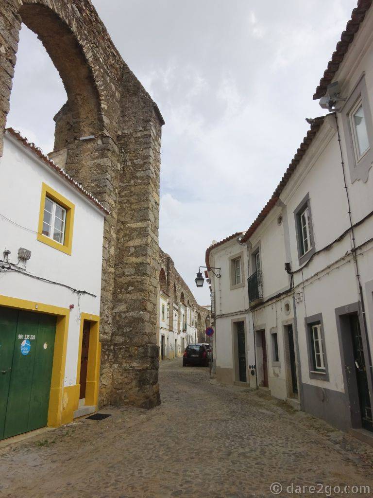Houses and shops fill in the spaces of the arches of the aqueduct in Evora.