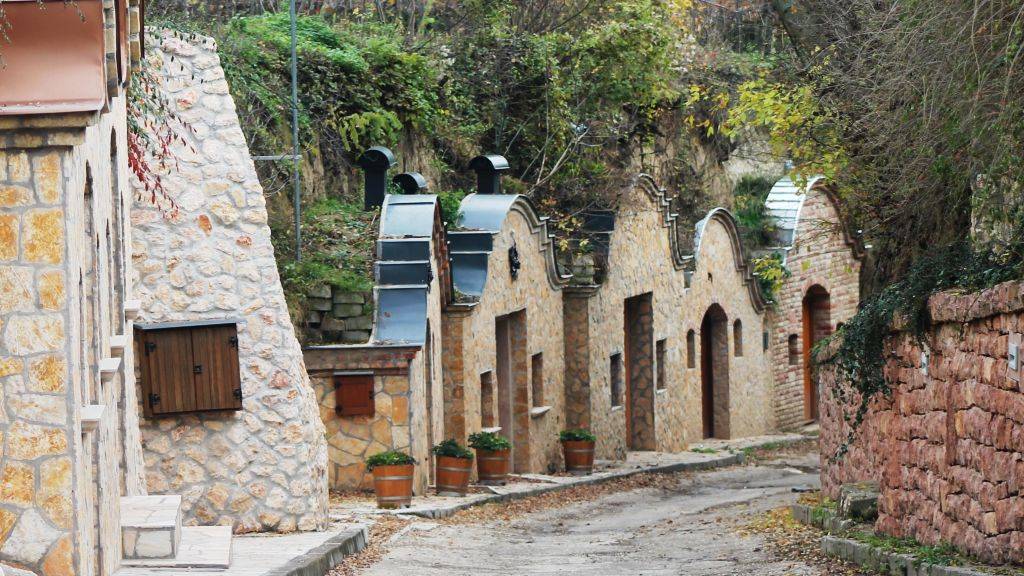 Hungary has a fairly unique style of wine cellars. They are built into a hill, covered with soil. Only in the front is a small, often cute, house for the pressing. This row of cellars is in Nyúl, on the road to the Pannonhalma Archabbey.