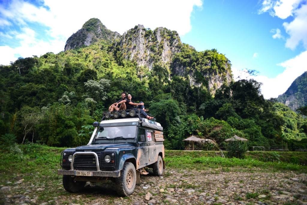 Overlanding can be so interesting! Get off the road and enjoy some beautiful countryside [2 people sitting on top of a Landrover]