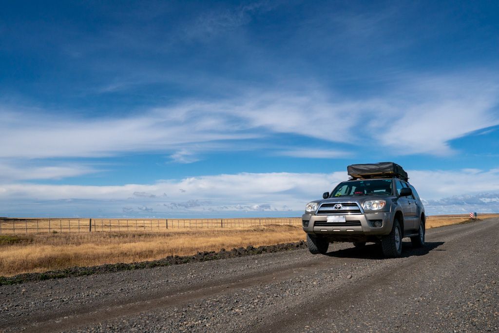 An overland traveller's vehicle on a long, straight, gravel road.