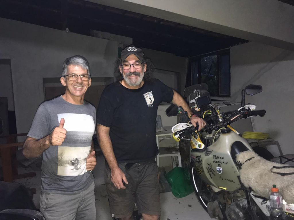Dan with his bike in lockdown in Brazil. Standing next to him is Luis, who helped him find this place to stay.