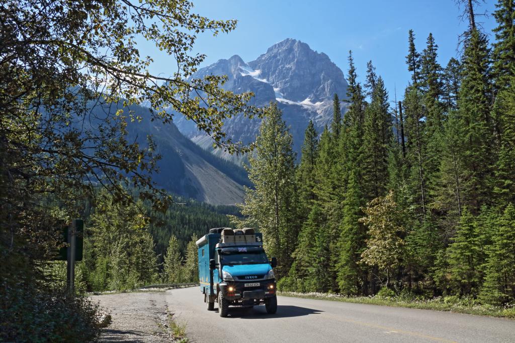 Very impressed to drive through the stunning Rockies in Canada (camper on a road with high mountains in the background)