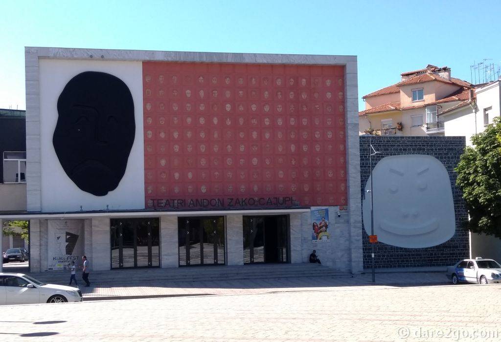 The Facade of the Andon Zako Çajupi Theatre: on the left the sad face in black, in the centre the collection of clay masks, on the right the happy face in white.